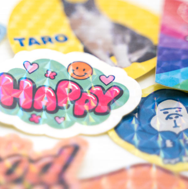 「HAPPY」のロゴを印刷した、モザイクのホログラムシールのアップ